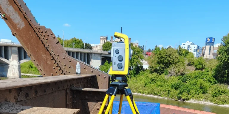 Robotic total station on a tripod set up on a steel truss bridge during construction layout